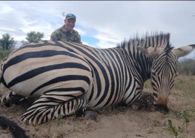 A hunter with his prize zebra